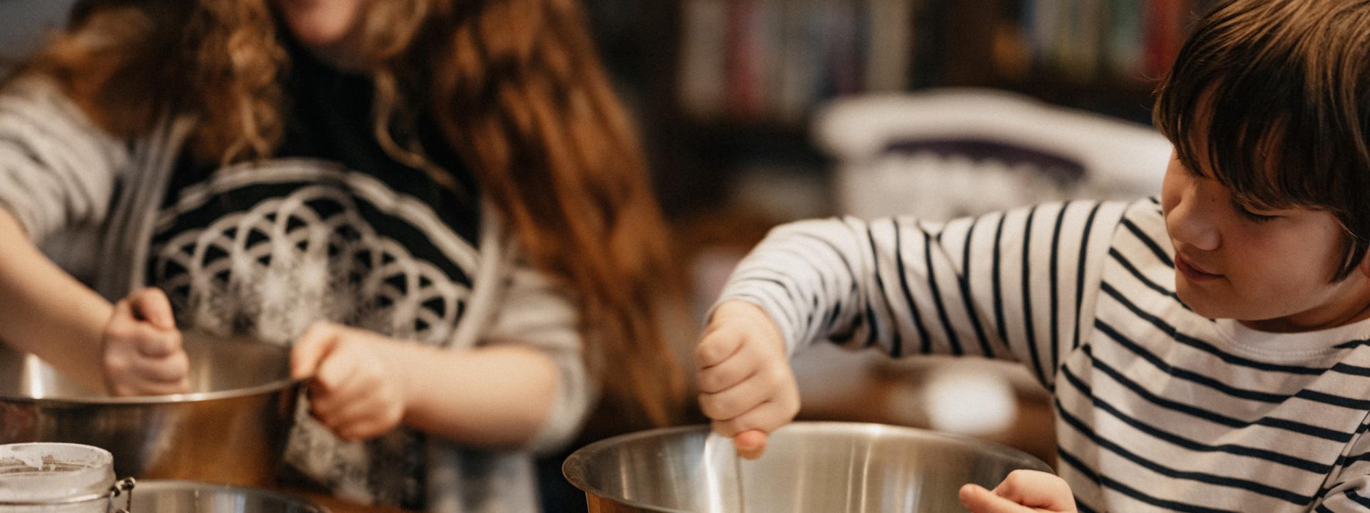 Kinder rühren am Tisch in Schüsseln