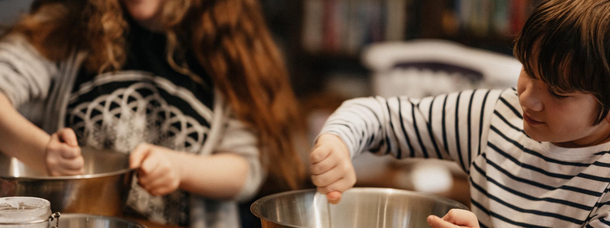 Kinder rühren am Tisch in Schüsseln